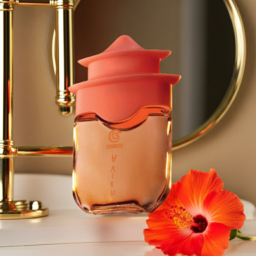 Haiku Sunrise Eau De Perfume bottle with orange cap and vibrant hibiscus flower on white surface
