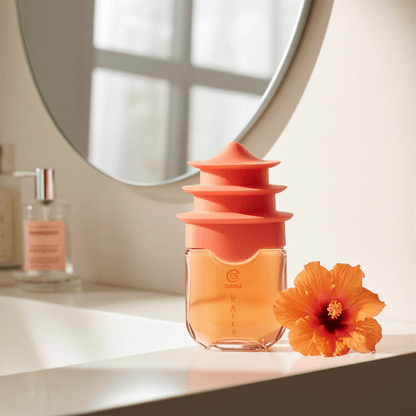 Haiku Sunrise Eau De Perfume 1.7 fl oz bottle with orange floral cap and hibiscus flower on white countertop under mirror