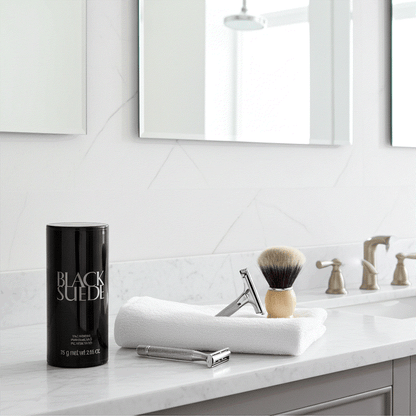 Black Suede talc powder 2.65 oz on bathroom counter with shaving brush and razor