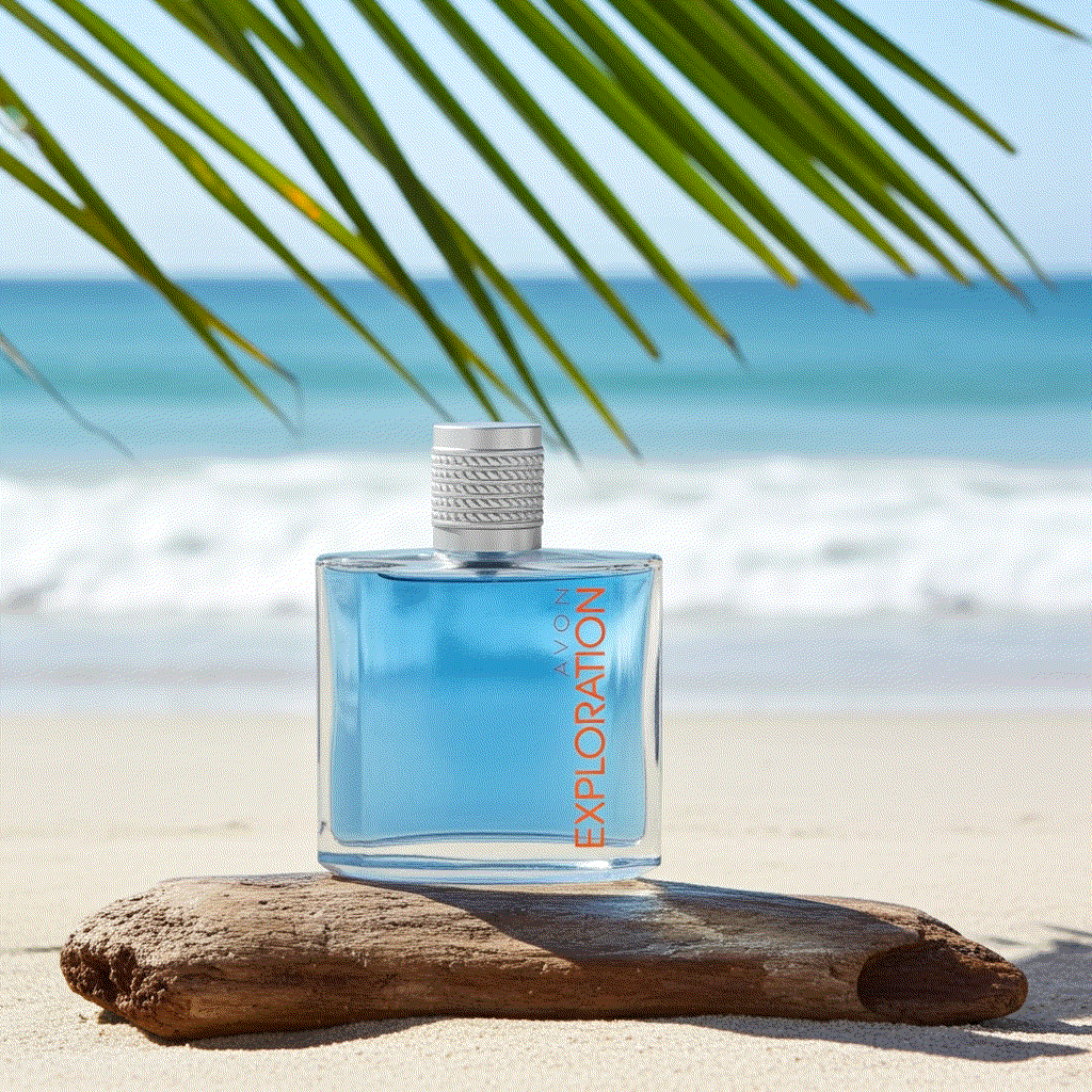 Avon Exploration Eau De Toilette cologne bottle with blue liquid on beach wood under palm leaves