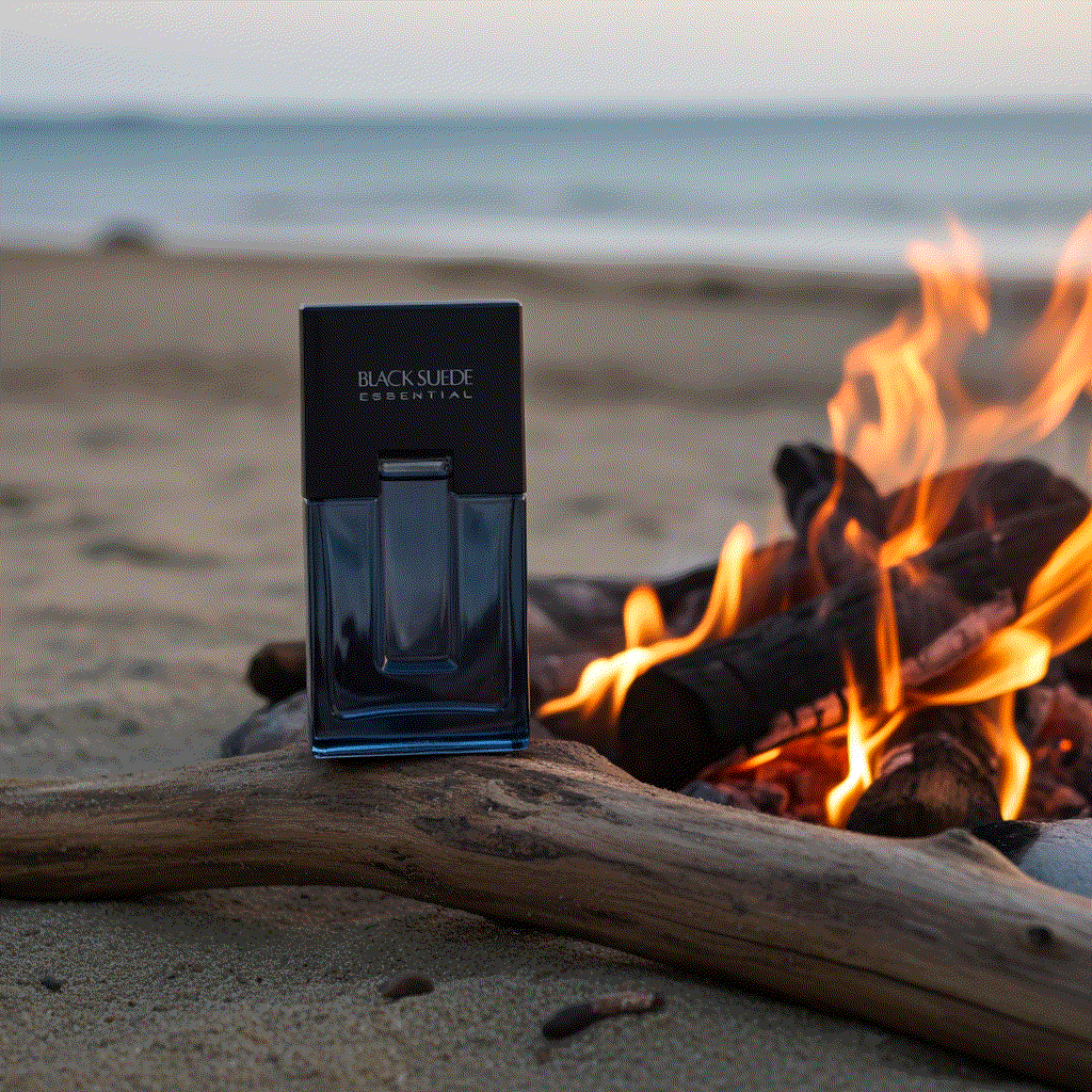 Black Suede Essentials men's cologne bottle on beach near fire with ocean background