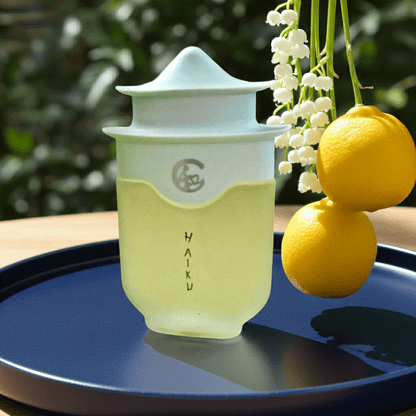 Avon Haiku Original Eau De Perfume bottle beside yellow yuzus on tray representing airy floral scent