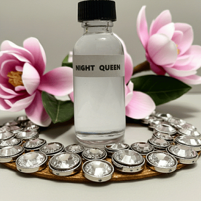 Night Queen perfume oil bottle with decorative crystals and pink flowers background